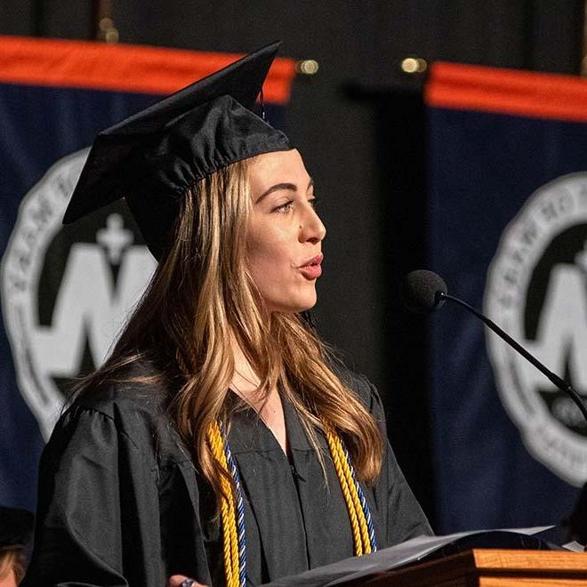 Female graduate speaking on stage at commencement