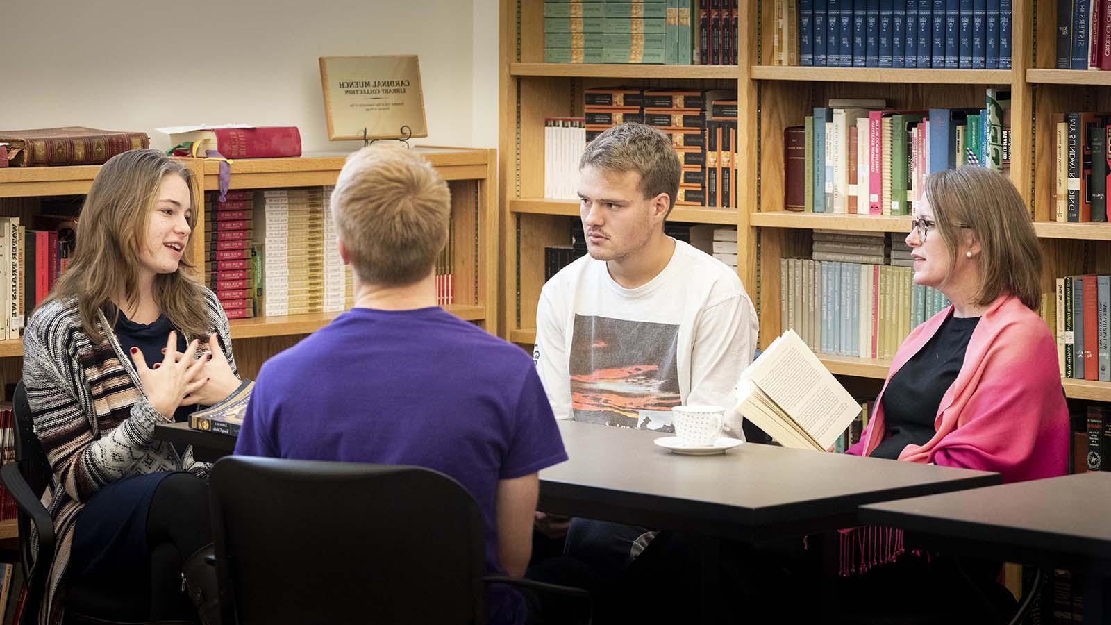 Three Catholic studies students in informal discussion with professor