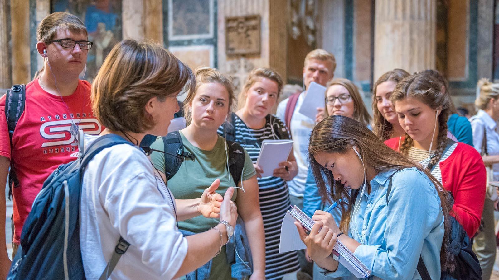 Study abroad students in the Pantheon in Rome, 意大利, taking notes while listening to lecture by a professor